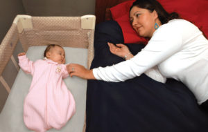 Image of mother reaching out to infant in a bassinet